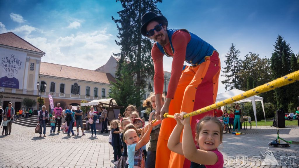 Gólyalábas artista interaktív gólyalábas műsorban kötélhúzás feladatot csinál gyerekekkel