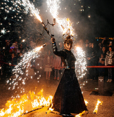 Szikrashow halloween-i sminkben szikrázó legyezőt forgat az előadó lángoló kosztümben